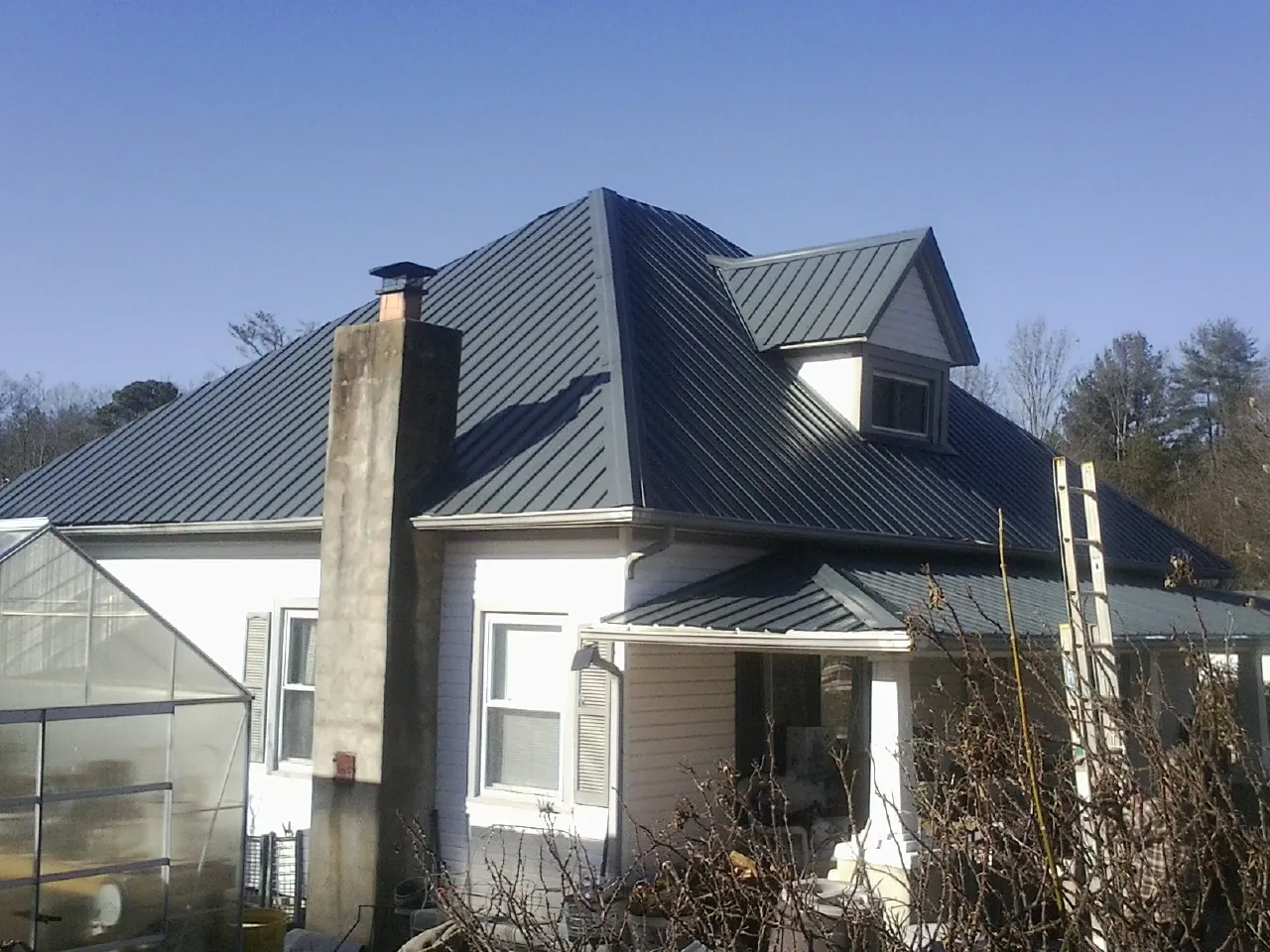 Dark blue standing seam metal roof on a white farmhouse with dormer — Slate & Tile Roof Repair by Roofing Brothers in Glassport