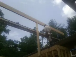 Carpenter setting a ridge beam over a new addition frame — Ice Dam Removal by Roofing Brothers in Glassport