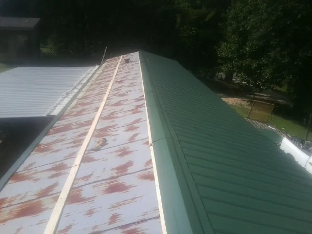 Old rusted panels beside newly installed green metal roofing — Wind Damage Roof Repair by Roofing Brothers in Glassport