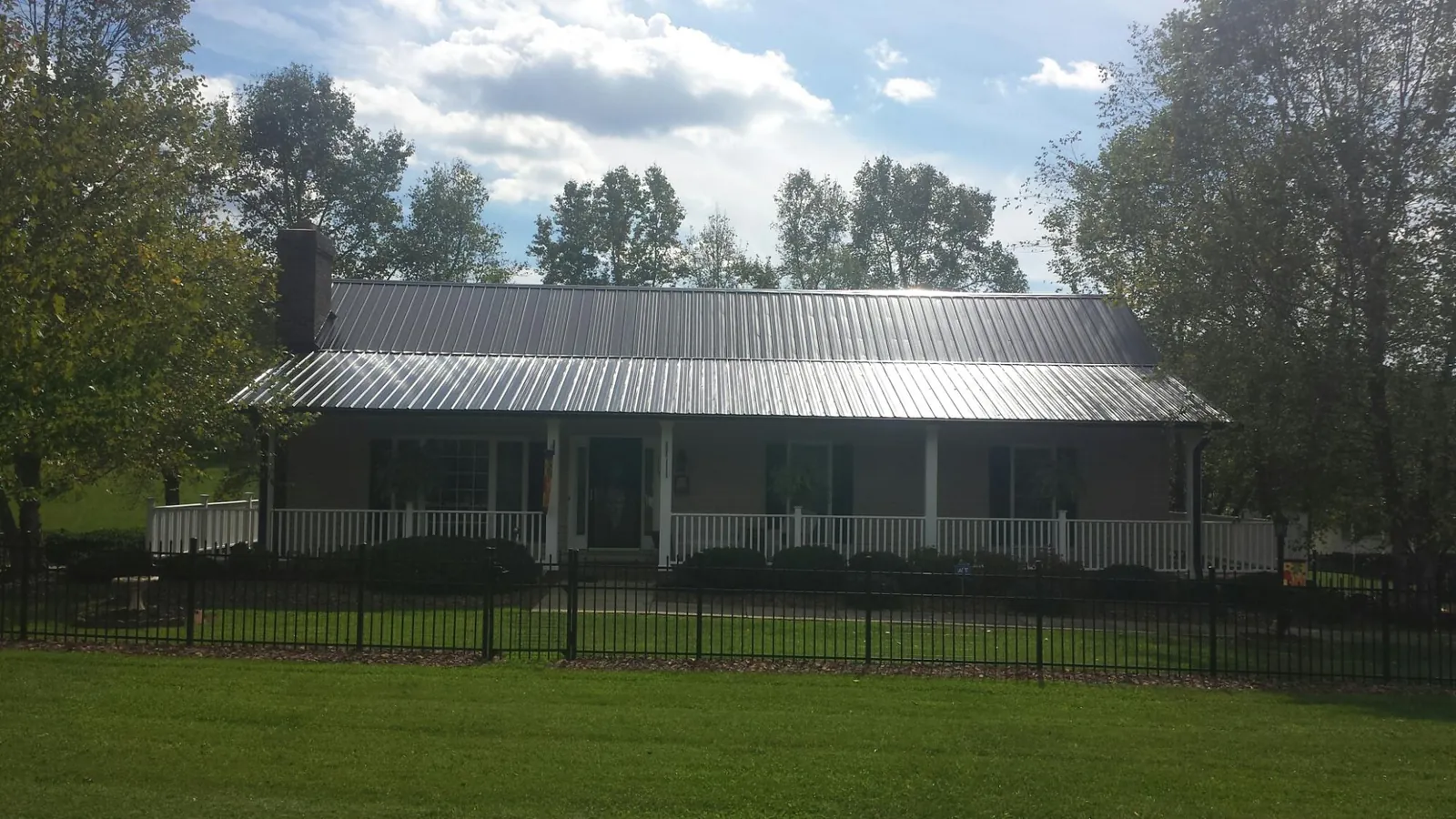 Gray metal roof on a brick ranch with a full width front porch — Gutter Guard Installation work by our crew in Glassport