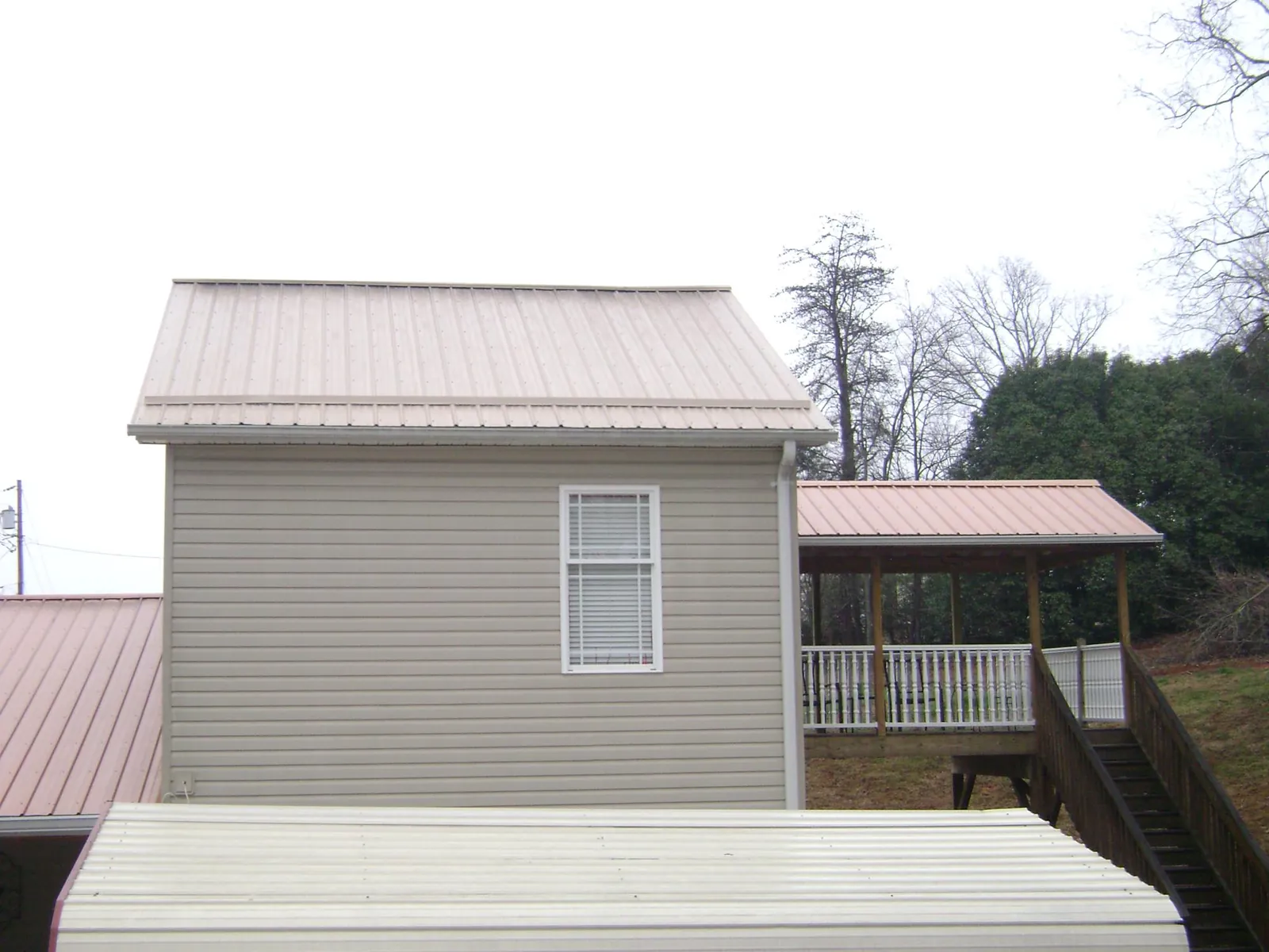 Tan metal roofs on a two story addition and attached porch, from a Roof Replacement job in Glassport