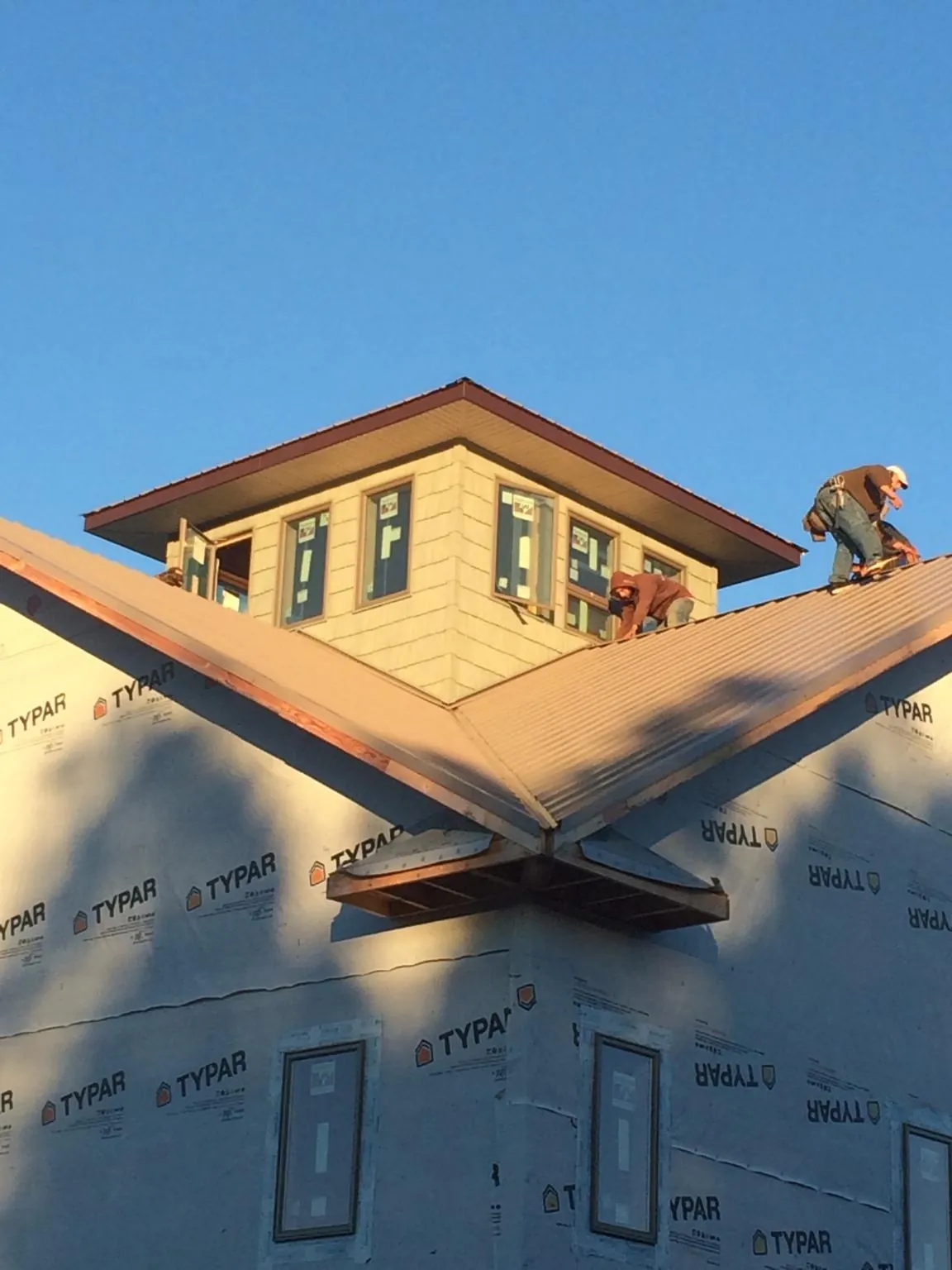 Roofers working around a rooftop cupola on a new metal roof at sunset — Roof Waterproofing in Glassport by Roofing Brothers